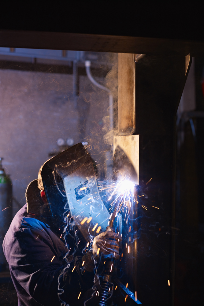 Industrial-welder-creating-sparks-while-working-on-a-metal-structure-—-representing-ASC-Factory’s-precision-and-craftsmanship فني لحام صناعي يعمل بدقة على هيكل معدني – يوضح احترافية مؤسسة ASC وجودتها في التصنيع