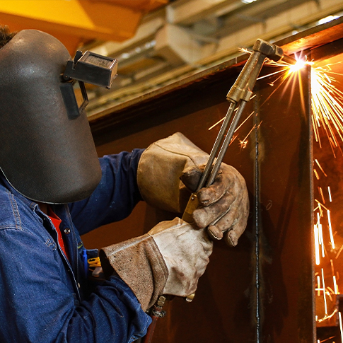 Welding-Technician-Using-Torch-Cutter-on-Steel فني لحام يستخدم شعلة قطع معدنية على شعاع فولاذي – يبرز احترافية مؤسسة ASC في خدمات اللحام والتصنيع